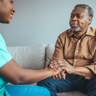 aid working holding hands with older man